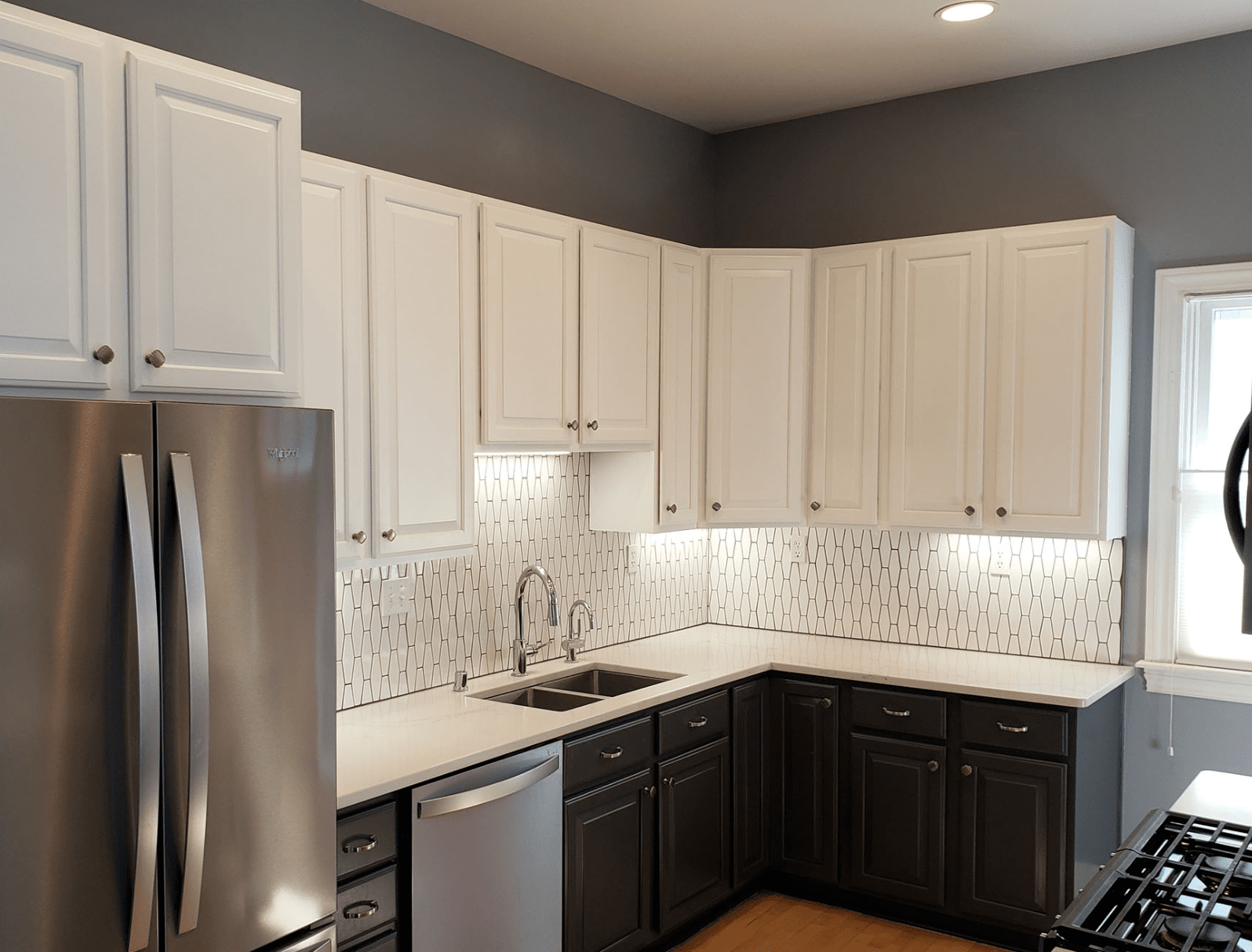 White cabinets with white tile and dark bottom cabinets.