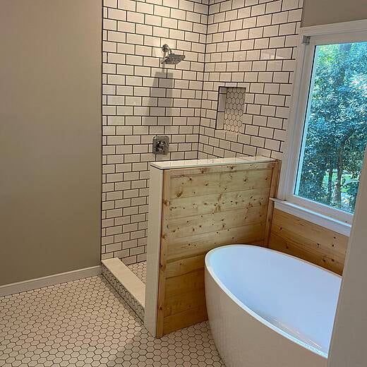 Bathroom with shower and oval tub under window.